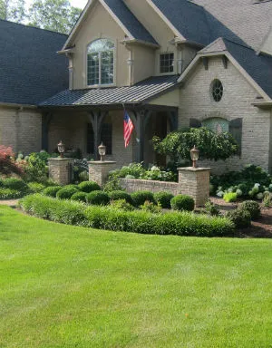 Image of Green Lawn with a brick house and beautiful landscaping job